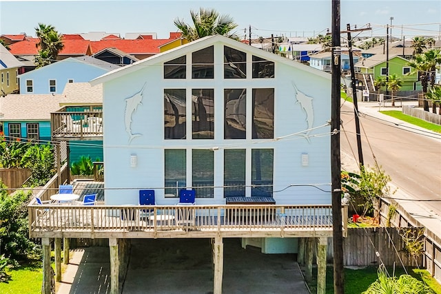 rear view of property with a wooden deck, a sunroom, and a carport