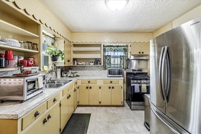 1032 Illinois St, Robstown, TX 78380 - kitchen featuring appliances with stainless steel finishes, open shelves, light countertops, cream cabinetry, and a textured ceiling