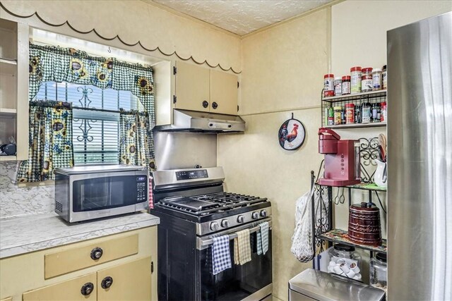1032 Illinois St, Robstown, TX 78380 - kitchen featuring appliances with stainless steel finishes, under cabinet range hood, light countertops, and cream cabinetry