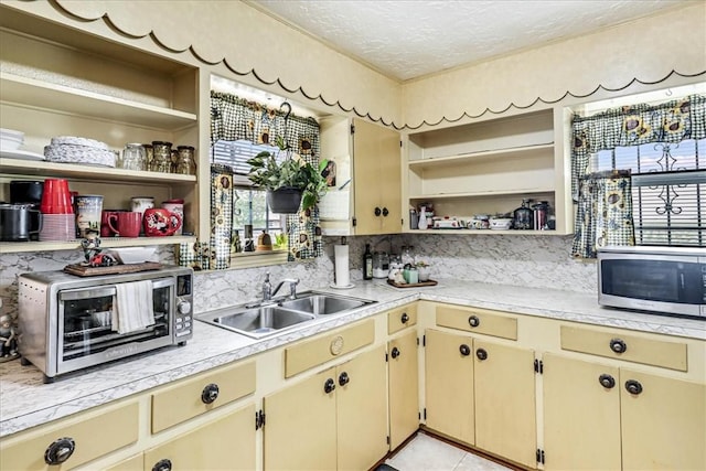 1032 Illinois St, Robstown, TX 78380 - kitchen featuring open shelves, stainless steel microwave, light countertops, cream cabinets, and plenty of natural light