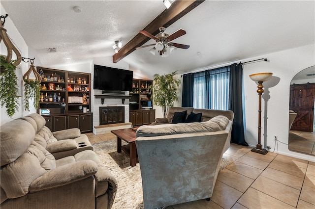 living room featuring lofted ceiling with beams, light tile patterned flooring, a barn door, a textured ceiling, and ceiling fan