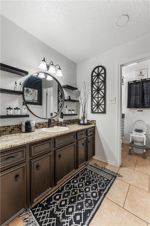 bathroom with tile patterned flooring, vanity, a textured ceiling, and toilet