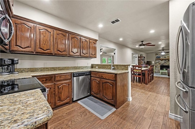 kitchen featuring a ceiling fan, visible vents, a sink, light wood-style floors, and stainless steel appliances