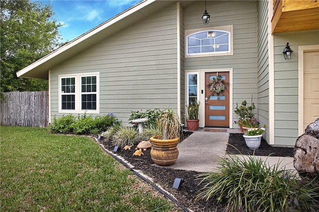 entrance to property featuring fence and a yard