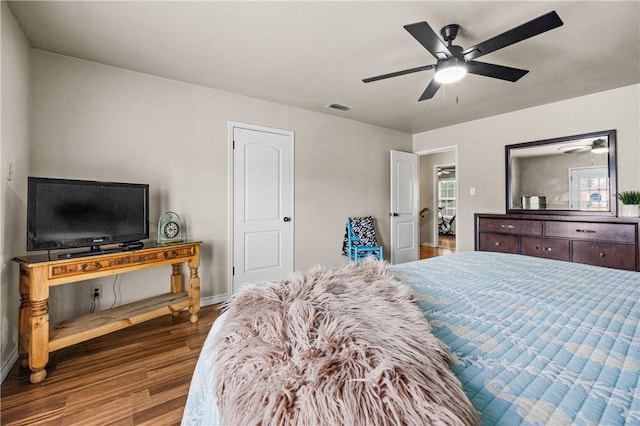bedroom featuring a ceiling fan, baseboards, visible vents, and wood finished floors