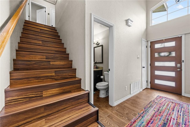 entrance foyer featuring visible vents, baseboards, wood finished floors, and stairway