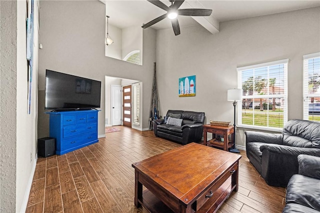 living area featuring dark wood-type flooring, baseboards, ceiling fan, and beam ceiling