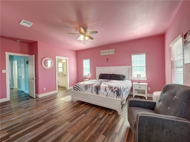 bedroom with dark wood-type flooring, ceiling fan, and connected bathroom