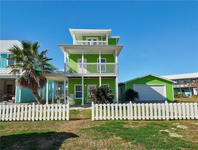 beach home with a garage, a front yard, and a balcony