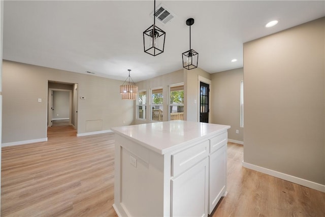 kitchen featuring white cabinetry, decorative light fixtures, a center island, a chandelier, and light hardwood / wood-style flooring