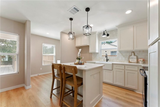 1233 Brentwood Dr, Corpus Christi, TX 78404 - kitchen featuring a sink, decorative backsplash, a kitchen island, white cabinets, and light countertops