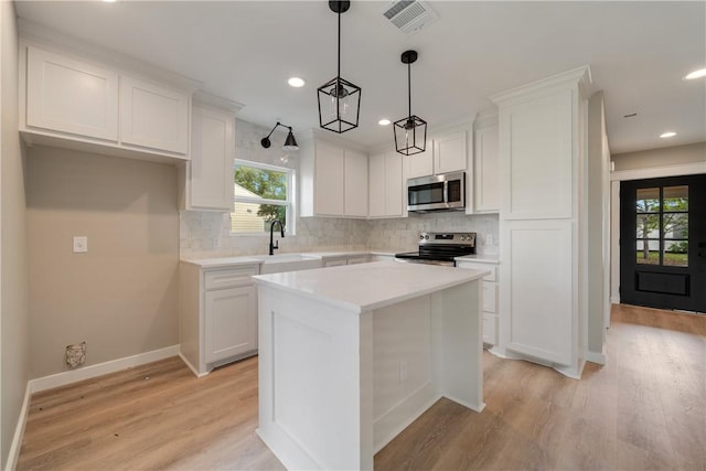 kitchen featuring pendant lighting, sink, white cabinetry, stainless steel appliances, and a center island