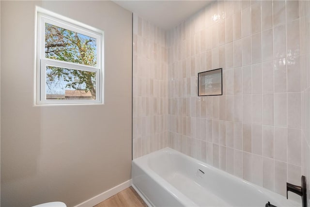 bathroom with tiled shower / bath combo and toilet