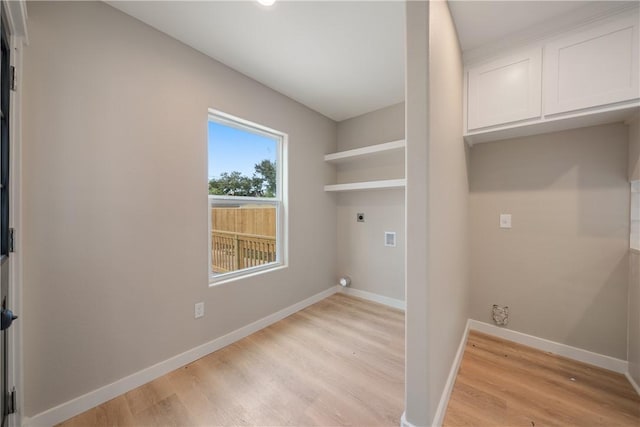 laundry area with electric dryer hookup, light hardwood / wood-style flooring, and cabinets