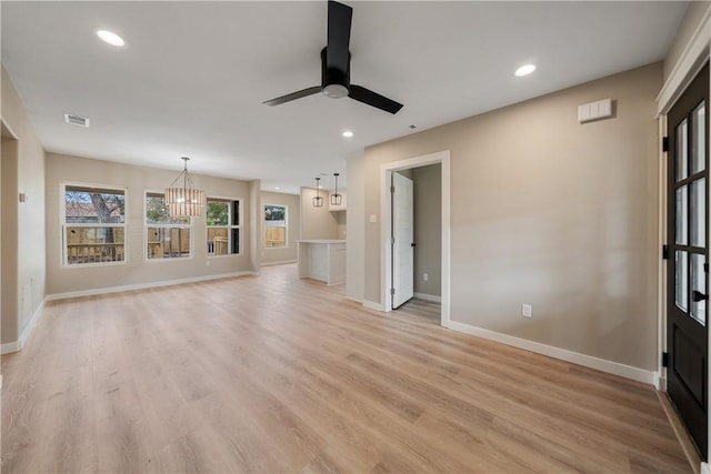 unfurnished living room featuring ceiling fan with notable chandelier and light hardwood / wood-style floors