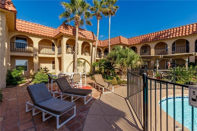 view of patio featuring a balcony and a community pool