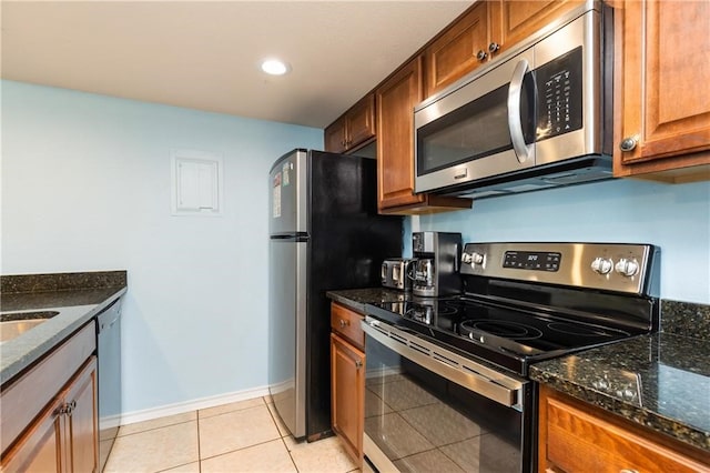 kitchen with dark stone counters, light tile patterned flooring, and appliances with stainless steel finishes