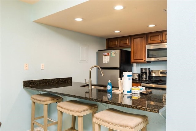 kitchen with dark stone counters, sink, a kitchen breakfast bar, and stainless steel appliances