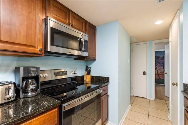 kitchen featuring dark stone counters, light tile patterned floors, and stainless steel appliances