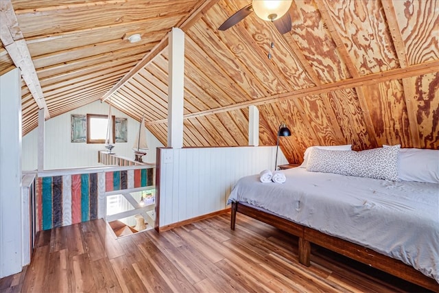 bedroom featuring hardwood / wood-style floors, ceiling fan, wood walls, and vaulted ceiling