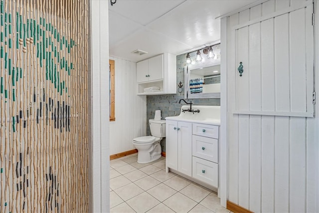 bathroom featuring toilet, vanity, wooden walls, and tile patterned floors