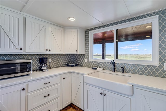 kitchen with tasteful backsplash, wood-type flooring, sink, and white cabinets