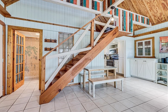 stairs with wood walls and tile patterned floors