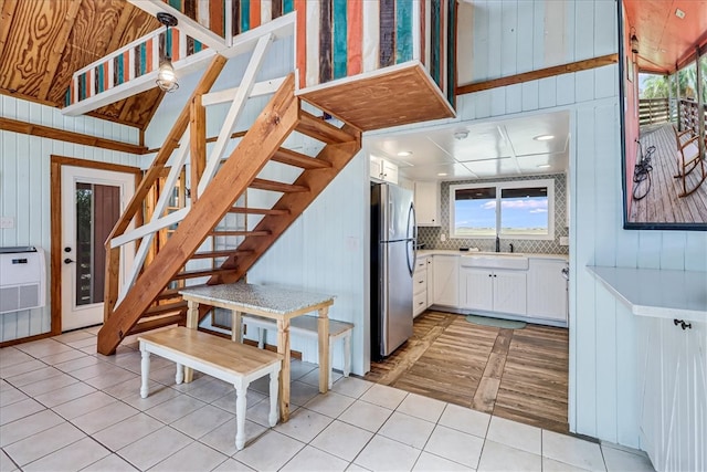 kitchen featuring white cabinets, wood walls, and stainless steel fridge