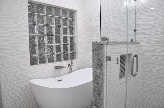 bathroom featuring shower with separate bathtub and tile walls