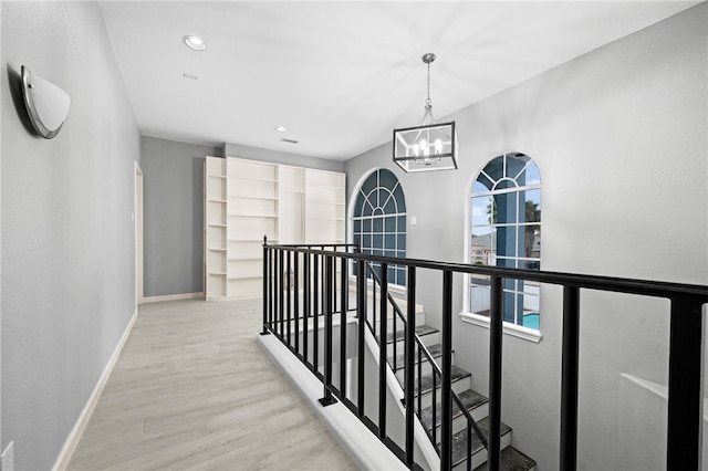 hall with light hardwood / wood-style flooring and an inviting chandelier