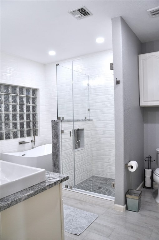 bathroom with a shower with door, vanity, wood-type flooring, and toilet