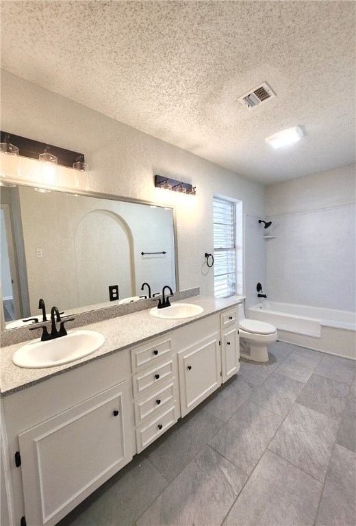 full bathroom with a textured ceiling, shower / washtub combination, vanity, and toilet