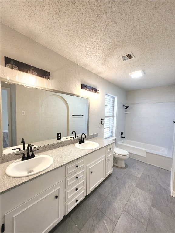 full bathroom featuring a textured ceiling, shower / washtub combination, vanity, and toilet