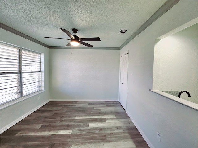 spare room with a textured ceiling, ceiling fan, crown molding, and wood-type flooring