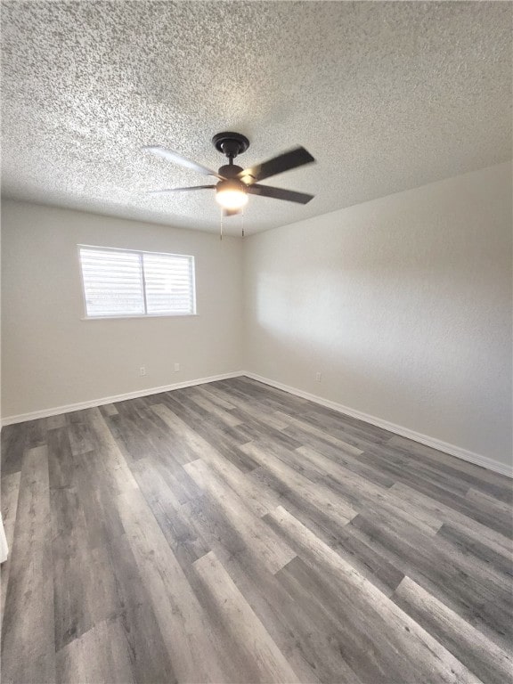 empty room with ceiling fan, dark hardwood / wood-style flooring, and a textured ceiling