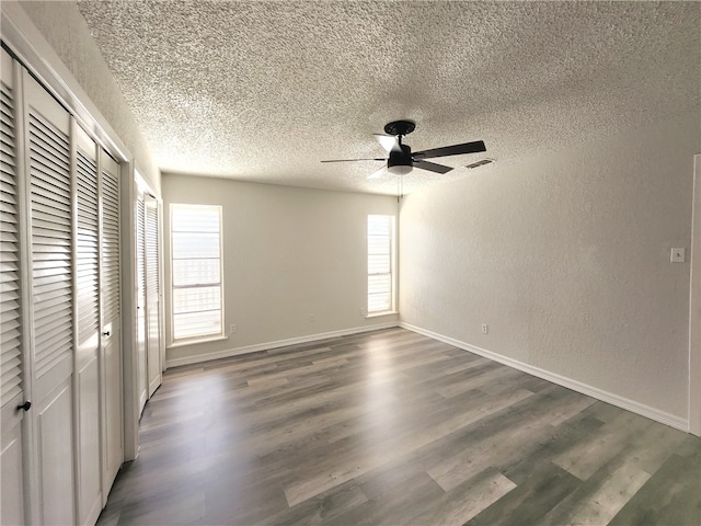 unfurnished bedroom featuring ceiling fan, a textured ceiling, and dark hardwood / wood-style floors