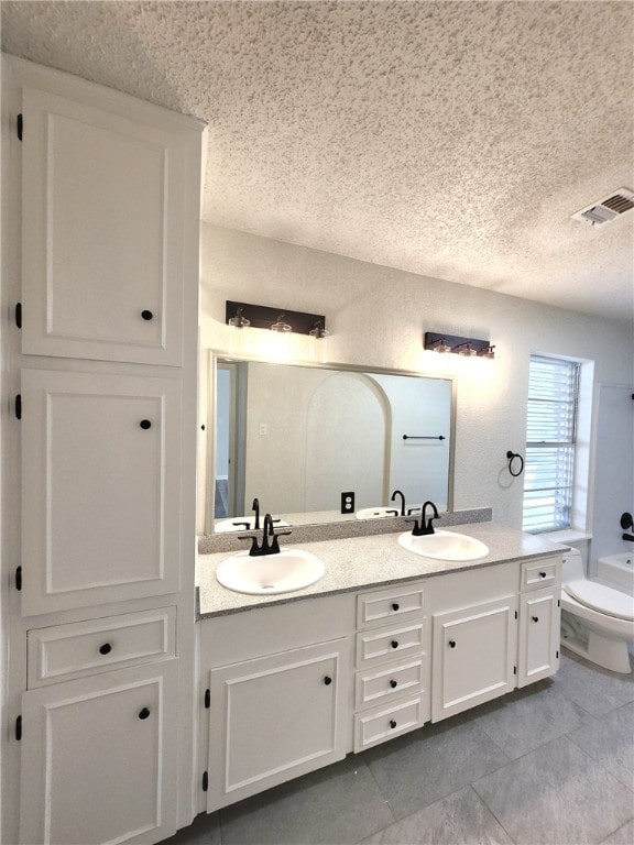 bathroom featuring toilet, tile patterned floors, vanity, and a textured ceiling