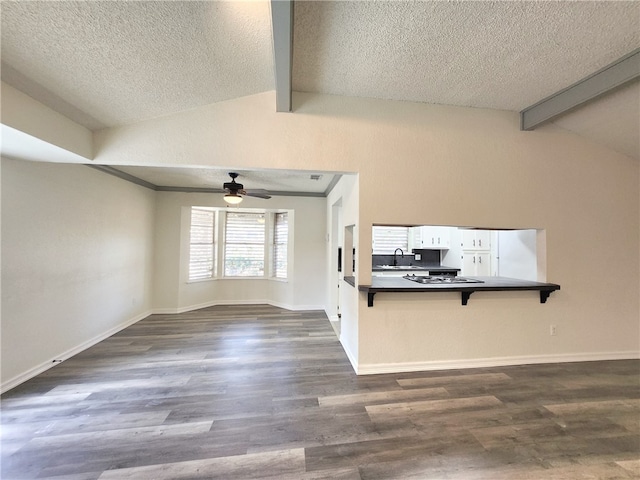 unfurnished living room with a textured ceiling, dark wood-type flooring, lofted ceiling with beams, and sink