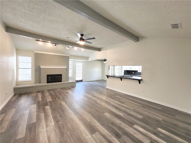 unfurnished living room with a textured ceiling, dark hardwood / wood-style flooring, lofted ceiling with beams, and a fireplace