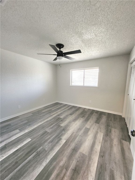 spare room featuring a textured ceiling and dark hardwood / wood-style flooring