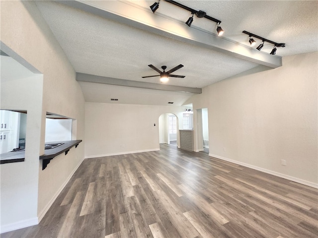 unfurnished living room featuring hardwood / wood-style flooring, track lighting, lofted ceiling with beams, and a textured ceiling