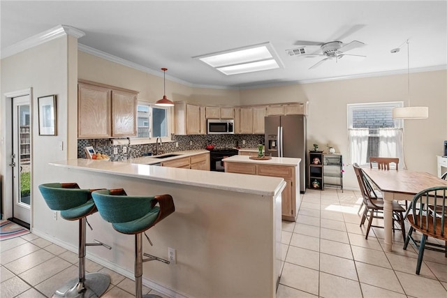 kitchen featuring stainless steel appliances, light countertops, light brown cabinets, and tasteful backsplash