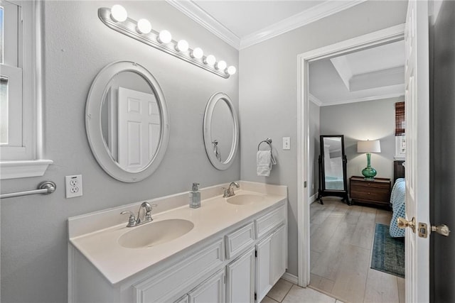 bathroom featuring double vanity, wood finished floors, a sink, and crown molding