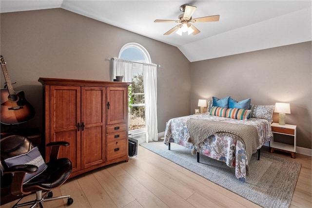 bedroom with vaulted ceiling, light wood-type flooring, a ceiling fan, and baseboards