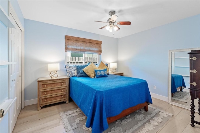 bedroom with light wood-type flooring, a closet, baseboards, and a ceiling fan