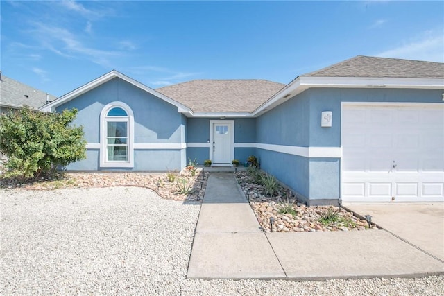 single story home with a garage, a shingled roof, and stucco siding