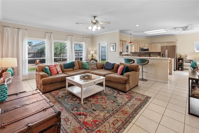 living area featuring light tile patterned floors, ornamental molding, visible vents, and a ceiling fan