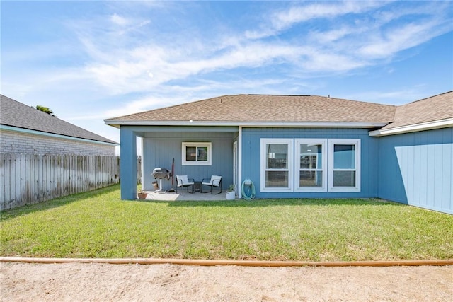 rear view of house with a yard, roof with shingles, a patio area, and a fenced backyard