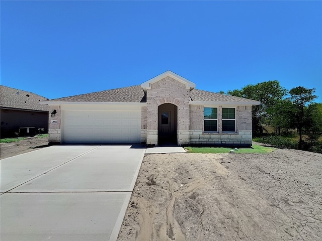 3002 Stone Creek Dr, Corpus Christi, TX 78410 - view of front of home featuring driveway, a garage, stone siding, brick siding, and roof with shingles