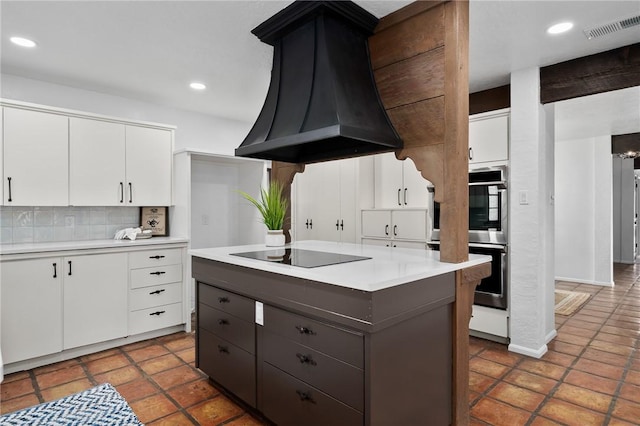 kitchen featuring a center island, white cabinets, decorative backsplash, black electric cooktop, and range hood